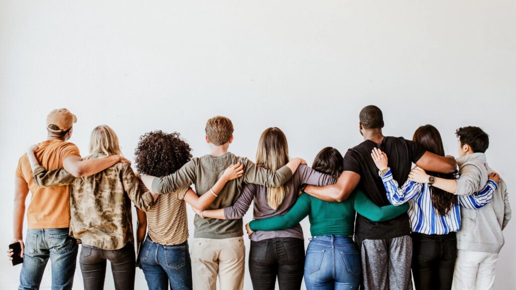 grupo de personas de espaldas, cogiéndose por los hombros, equipo unido